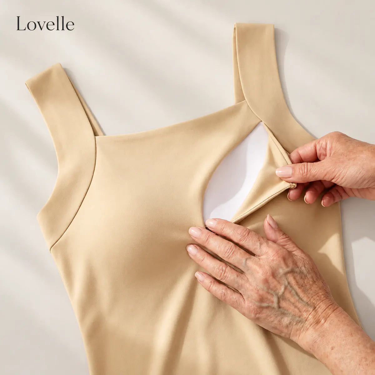Hands showing the pocket with the removable padding inside the Lovelle Ease built-in bra tank in nude