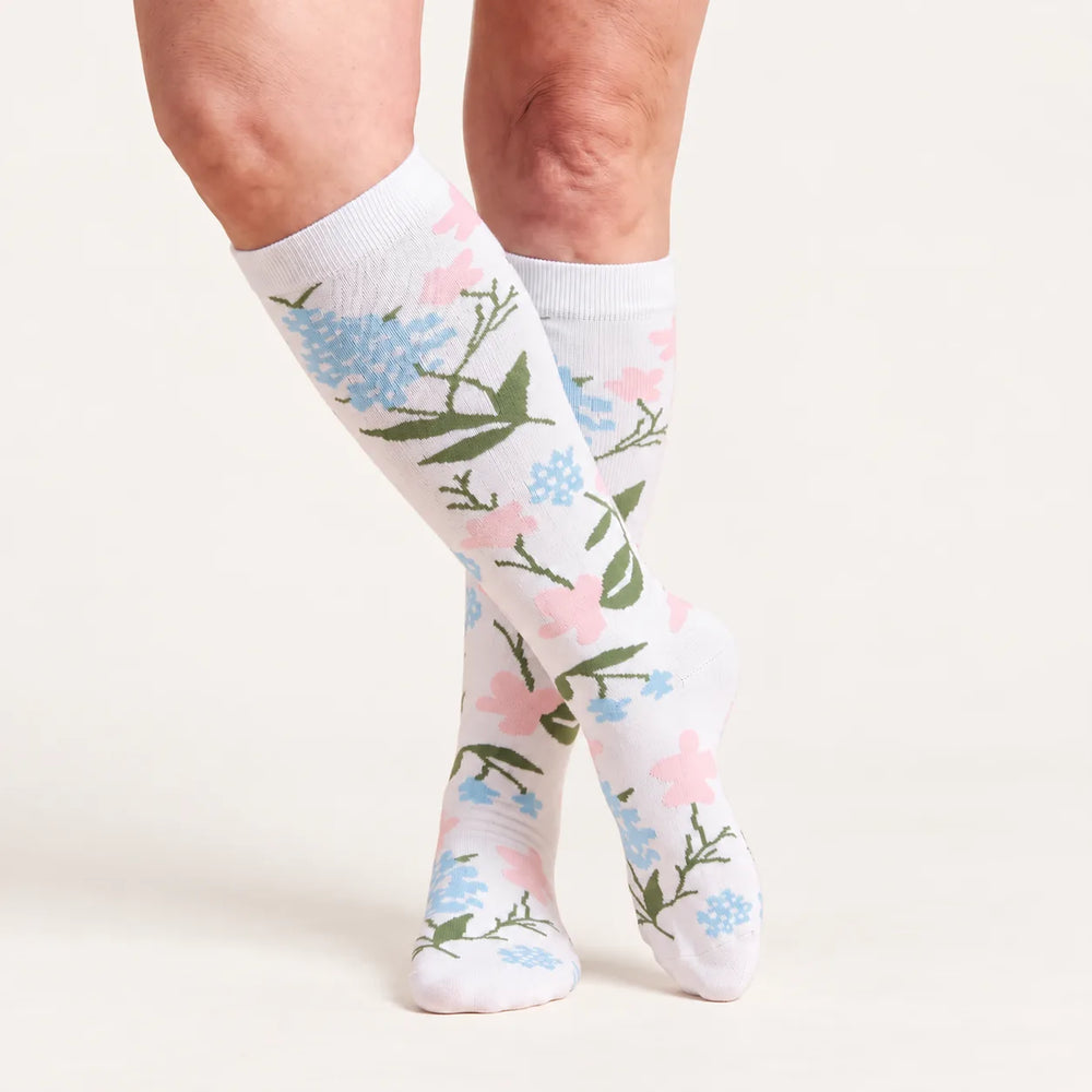 Lovelle Lift compression socks in White Meadow – knee-high, legs crossed
